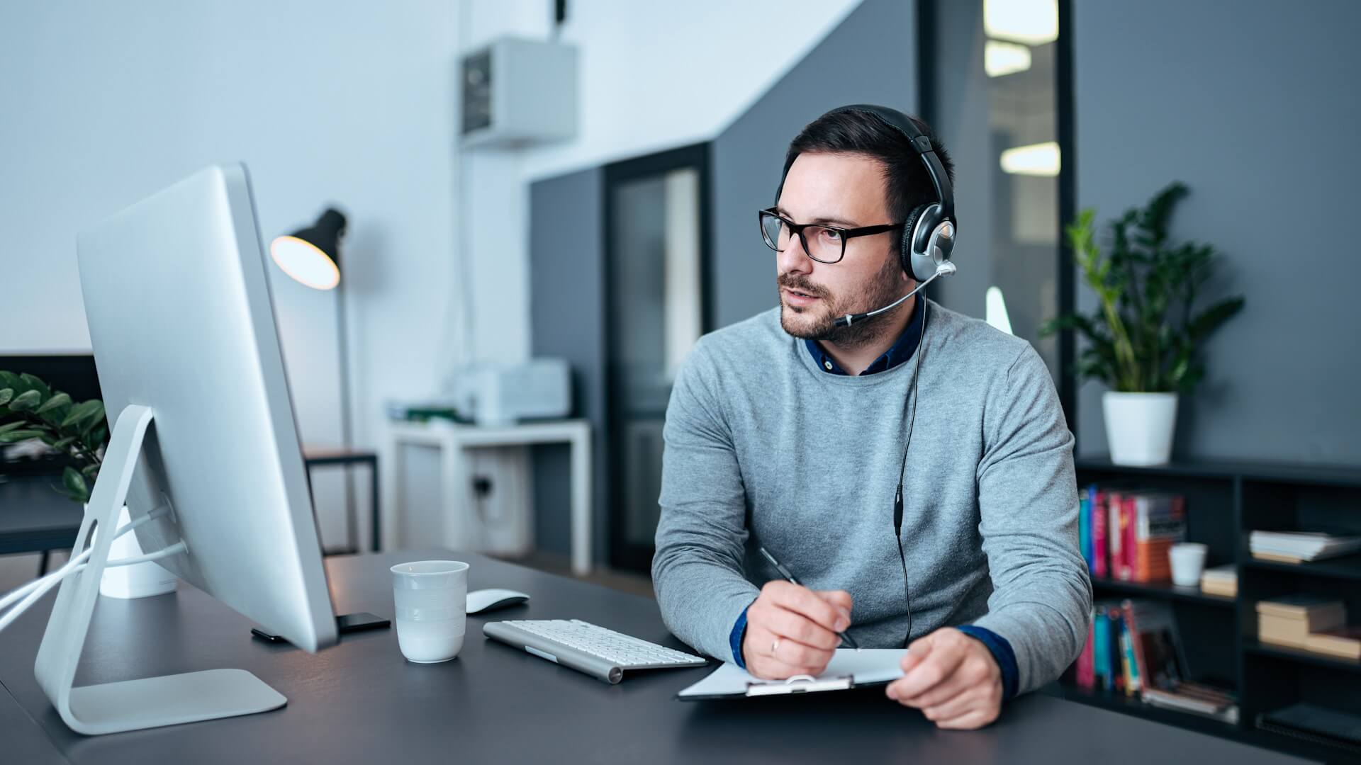 Pracownik działu  obsługi klienta ze  słuchawkami na  uszach w biurze